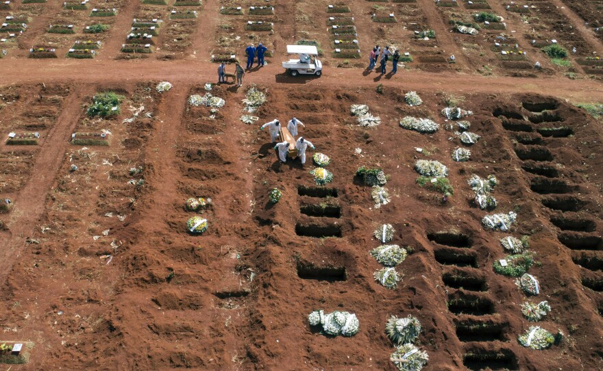 Cemetery workers wearing protective gear carry the coffin of a person who died from complications related to COVID-19 to a gravesite at the Vila Formosa cemetery in Sao Paulo, Brazil, Wednesday, April 7, 2021.