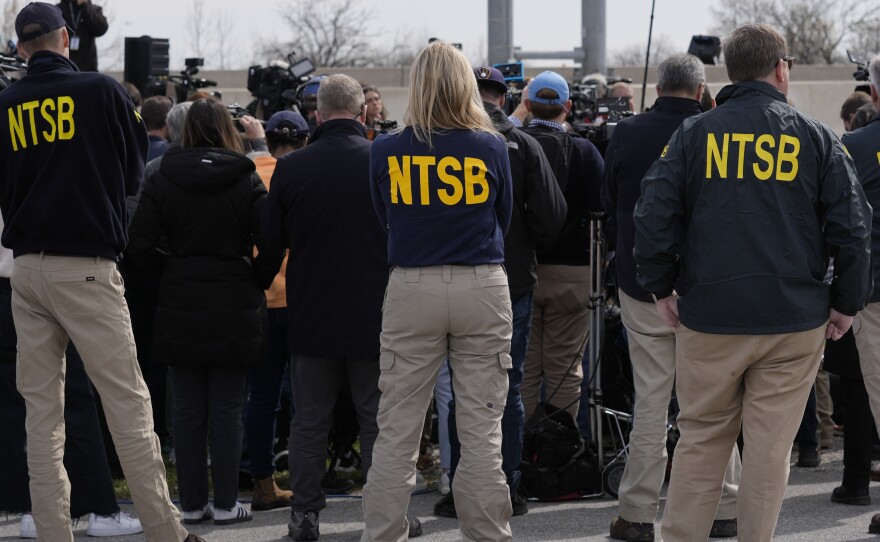 Members of the National Transportation Safety Board listen to NTSB Chair Jennifer Homendy speak during a news conference near the scene where a container ship collided with a support on the Francis Scott Key Bridge, in Dundalk, Md., Tuesday, March 26, 2024.