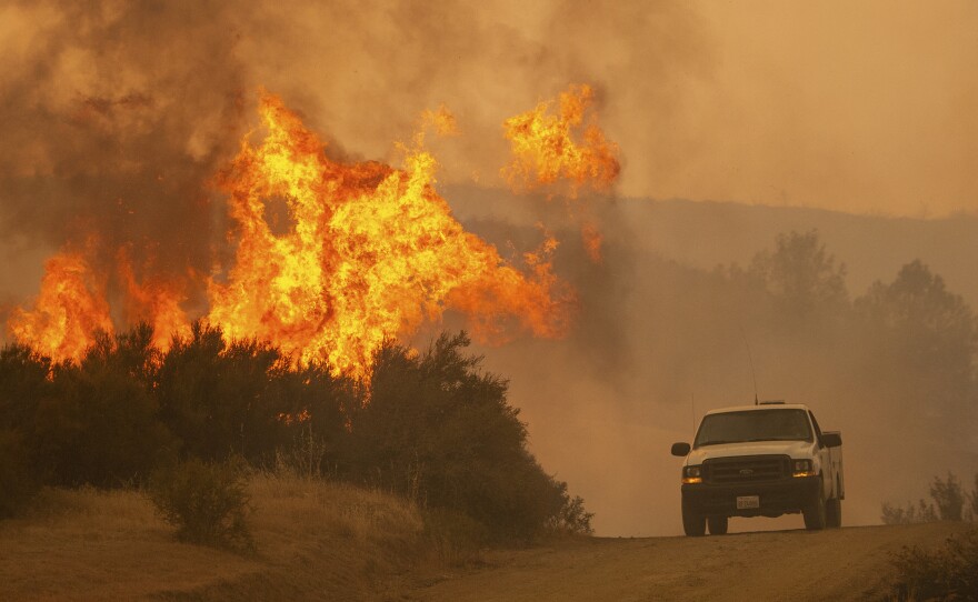 A truck passes by flames during the Ranch Fire in Clearlake Oaks, Calif., on Sunday, Aug. 5, 2018. 