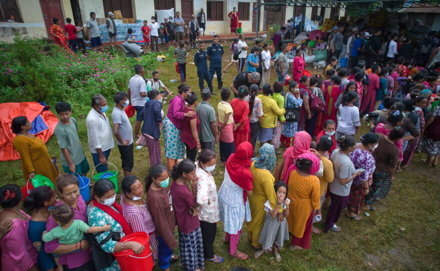People affected by recent flash floods stand in line to receive aid at a school converted into a temporary shelter in Nepal's Nuwakot district, Thursday.