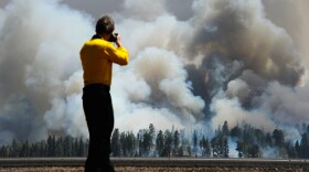 A photographer looks on as smoke rises around the Lee Valley Recreational area in the Apache National Forest on June 12, 2011 in Big Lake, Arizona. 