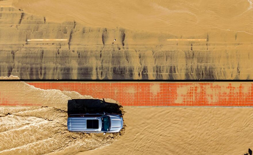 In this aerial picture taken on Aug. 21, a vehicle drives through floodwaters following heavy rains from Tropical Storm Hilary in Thousand Palms, Calif.