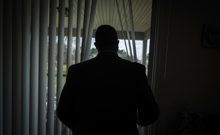 Joseph Moore looks out of a window at his home in Jacksonville, Fla. Today, he and his family live under new names.