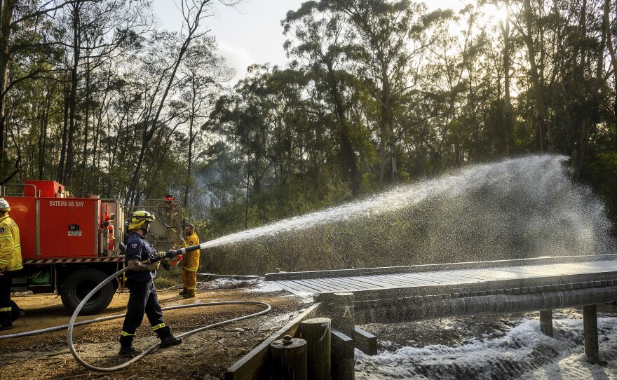 A firefighter coats a bridge with foam as a bushfire burns near Moruya, New South Wales, Australia, on Jan. 25. Wildfires destroyed more than 3,000 homes and razed more nearly 11 million hectares since the summer fires began.