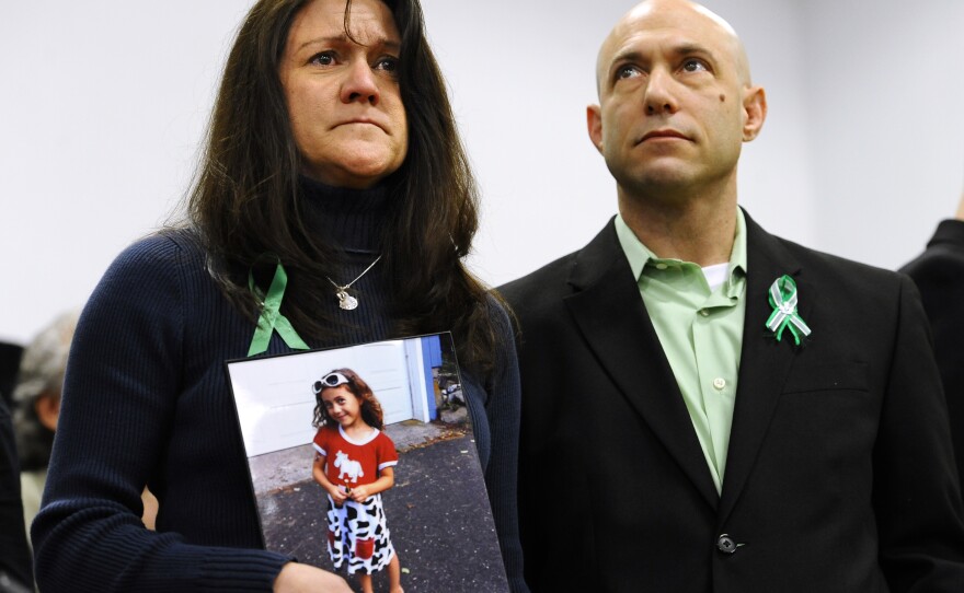 At a press conference one month after the shooting, Jennifer Hensel holds a portrait of her daughter, Avielle Rose Richman, who was among those killed at the Sandy Hook Elementary School. Beside her is her husband, Jeremy, who worked tirelessly for brain research into the causes of violence. Jeremy took his own life in 2019.