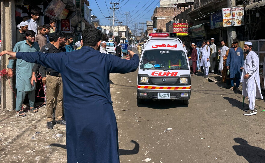 A volunteer clears the way for an ambulance transporting injured school children following a roof collapse at a private school in Peshawar, Pakistan, Thursday, Oct. 15, 2026.