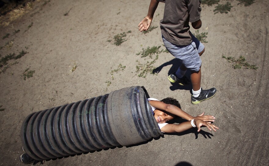 Ten-year-old Deion Jefferson and 7-year-old Samuel Jefferson push and roll a piece of culvert piping down a hill.