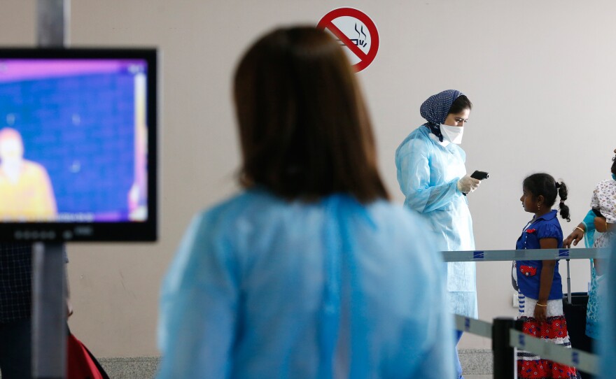 Temperatures are taken two ways at Casablanca's airport: with an infrared body scanner (left) and a handheld thermometer (right).