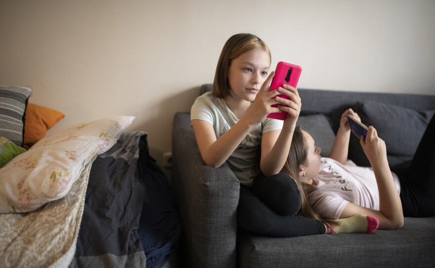 Oleksandra Nykolyn, left, and her sister Julija, right, use smartphones at their apartment in Sofia, Bulgaria, on Friday, April 22.