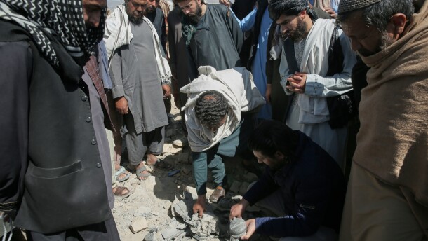 Residents and Taliban police gather the remains of a projectile at the site of a strike in Kabul, Afghanistan, on March 13.