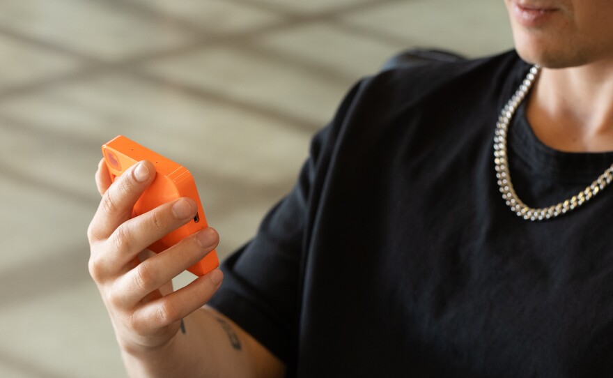 A Rabbit employee demonstrates the company's Rabbit R1 device. The company says more than 80,000 people have preordered the device for $199.