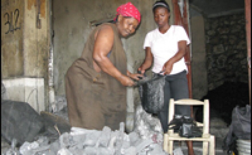 A charcoal seller scoops charcoal into a customer's bag at a market in Port-au-Prince. Charcoal is the main cooking fuel for most Haitians