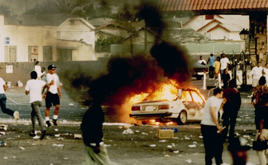 A car burns as looters take to the streets at the intersection of Florence and Normandie avenues — considered the flashpoint of the LA riots — on April 29, 1992.