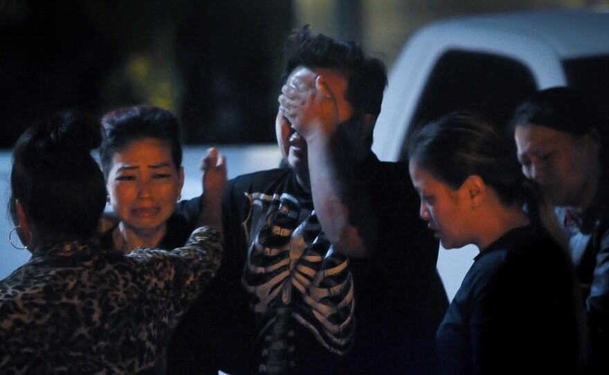 People console one another near the backyard where 10 men were shot, four fatally, on Sunday evening in Fresno, Calif.