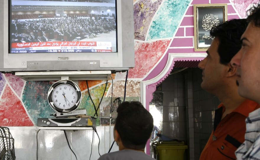 Iraqis follow a June 14 parliamentary session on local TV at a barbershop in Baghdad.