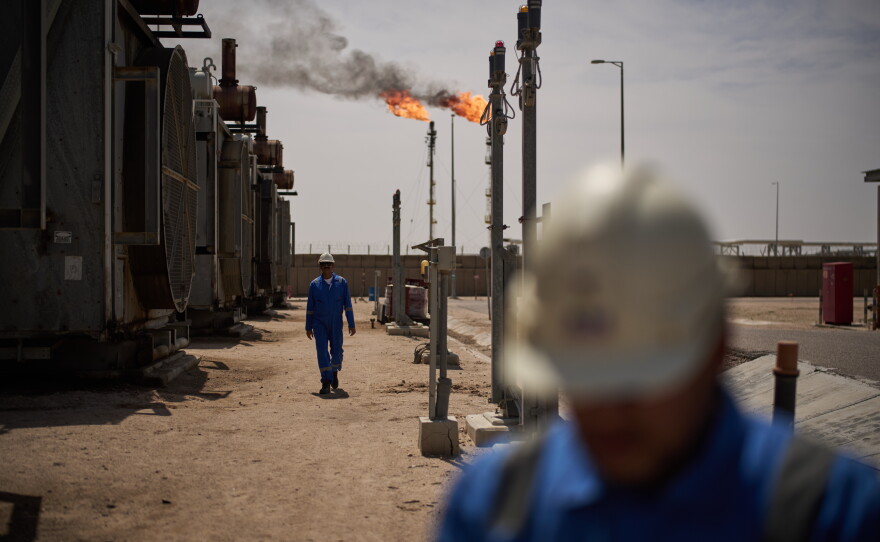 Workers walk in the Zubair oil field, whose operations have being reduced since the start of the Iran war, near Basra, Iraq, March 28.