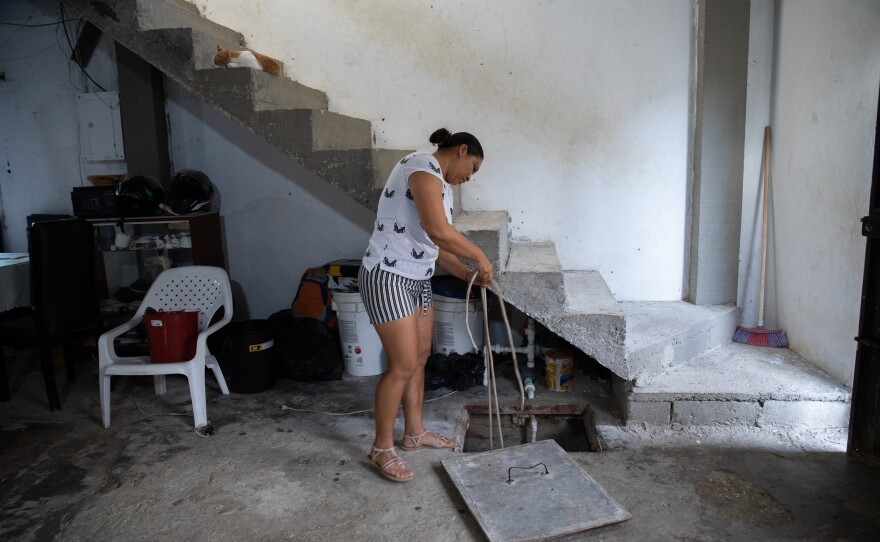 July Merino shows how she retrieves water from the <em>alberca</em> in her home. The concrete cistern can store about two weeks of water that her family uses to do laundry, wash dishes and flush the toilet.