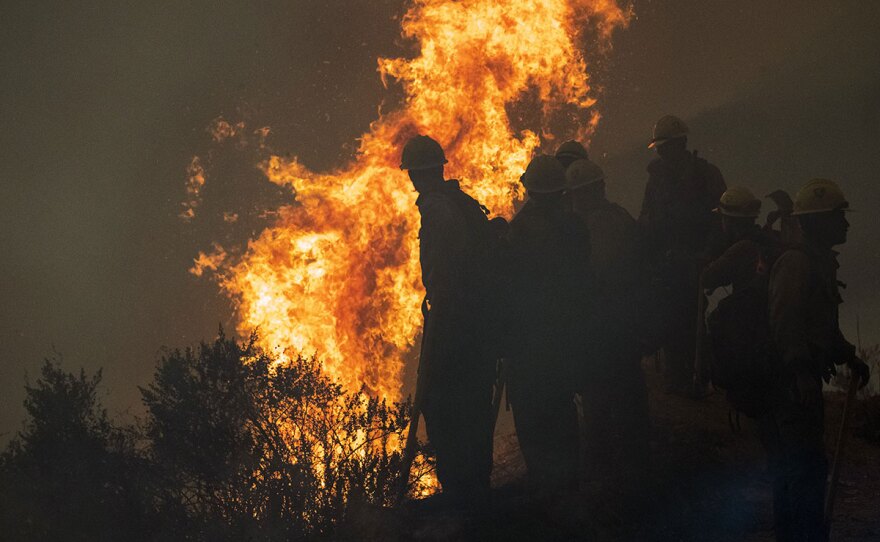 Firefighters monitor a controlled burn along Nacimiento-Fergusson Road to help contain the Dolan Fire near Big Sur, Calif., Friday, Sept. 11, 2020.