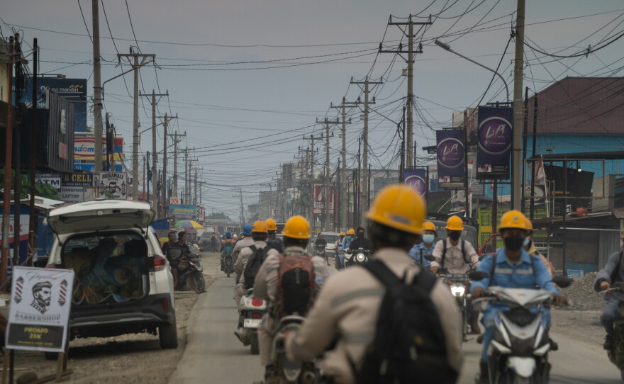 Workers travel to and from the Indonesia Morowali Industrial Park in Bahodopi, Indonesia. Smog from the coal plants that power the industrial park covers the area.