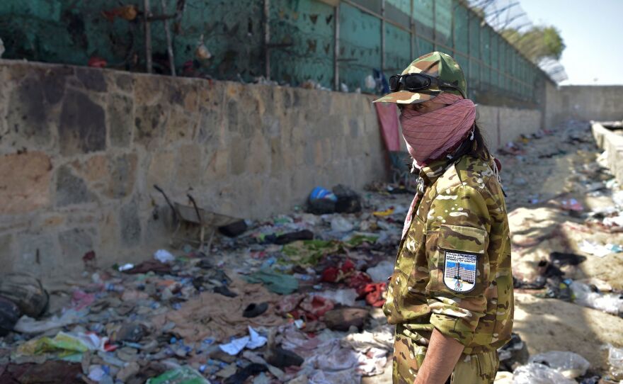 A Taliban fighter stands guard at the site of Thursday's bombing, blamed on the ISIS-K group, which killed scores of people including 13 U.S. troops, near the Kabul airport.