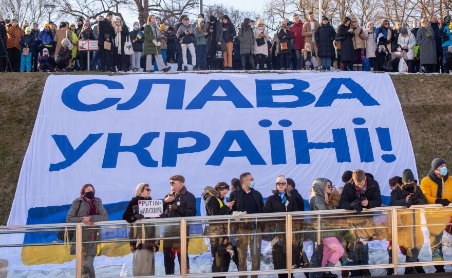 People stand in front of a huge banner with the lettering "Slava Ukraini" as they take part in a demonstration in support of Ukraine on Freedom Square in Tallinn, Estonia, on Feb. 26.