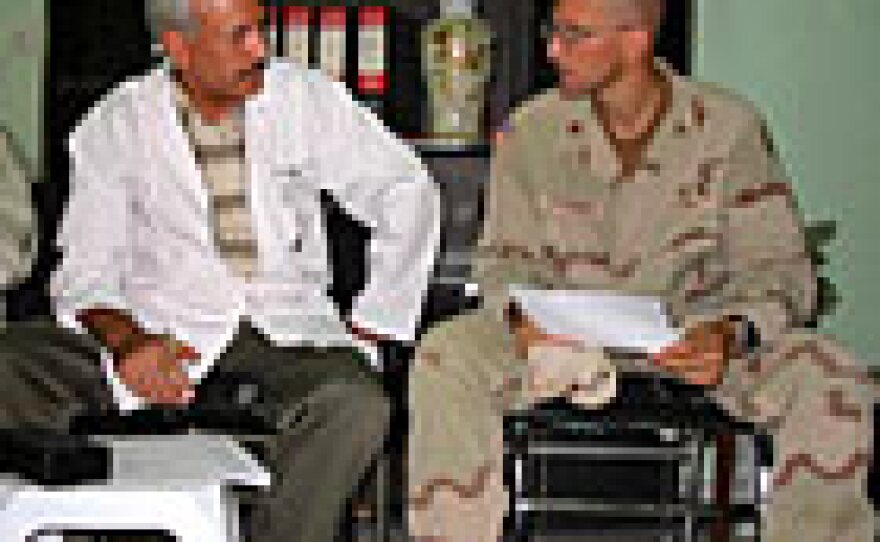 Dr. Abdul Jabar of Fallujah Hospital, left, and U.S. Army Maj. Mark Passamonti talk about getting a new X-ray machine for the hospital.