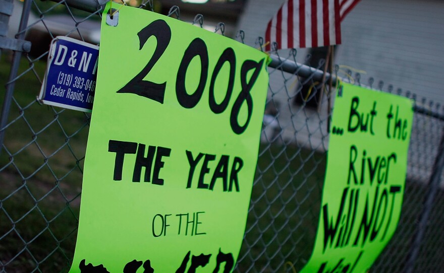 Signs reading "2008 the year of the river, but the river will not win!"' in June 2008. The flood that year served as a wake up call to the community about the vulnerability of its water infrastructure to extreme weather events.