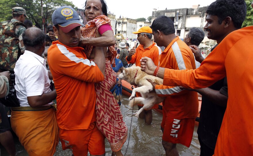 An elderly woman and a dog are carried from floodwaters by National Disaster Response Force personnel.