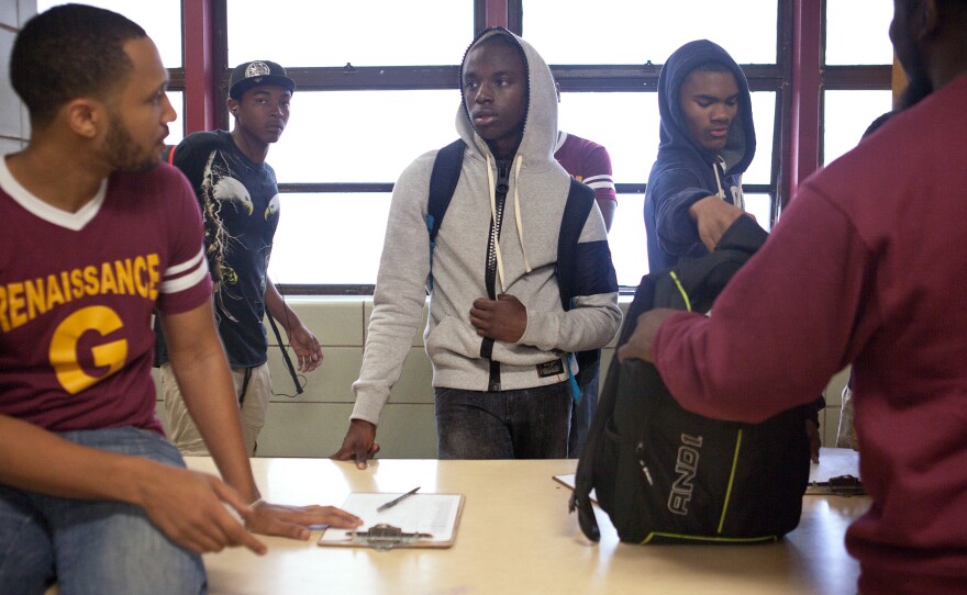 Marcus Taylor (left) greets student Kyree McRae, 16, as he checks into morning classes.