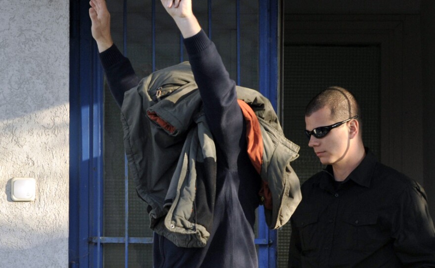 Zoltan Bakonyi is escorted by a police officer after being released from police custody in Veszprem, Hungary, on Wednesday. A broken reservoir at Bakonyi's aluminum company, MAL Rt, flooded towns in western Hungary with toxic red sludge.
