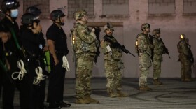 National Guardsmen and Los Angeles police officers stand guard as protests over the death of George Floyd continue Sunday, May 31, 2020, in Los Angeles.
