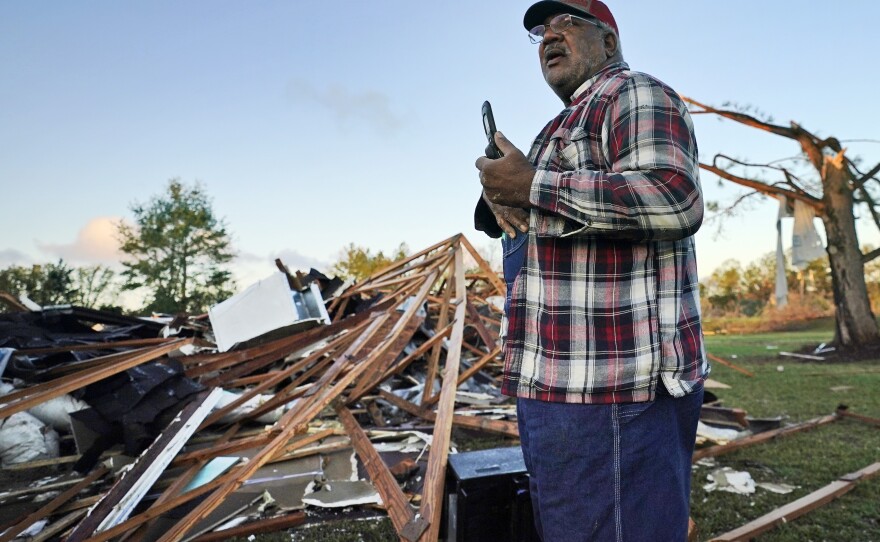 Fred Davis talks to his daughter on a cellphone on Saturday as he describes the damage to his home after a tornado hit in Powderly, Texas.