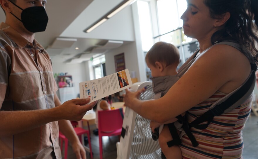 Mason Dow, a member of Climate Smart Missoula, gives a free air filter to a new mother at a local food bank, explaining the impacts of wildfire smoke on human health.