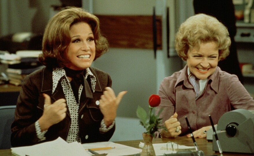 Mary Tyler Moore (left, as Mary Richards) gives a 'thumbs up' sign as she sits at her desk with Betty White (as Sue Ann Nivens) in a scene from 'The Mary Tyler Moore Show' in 1975.