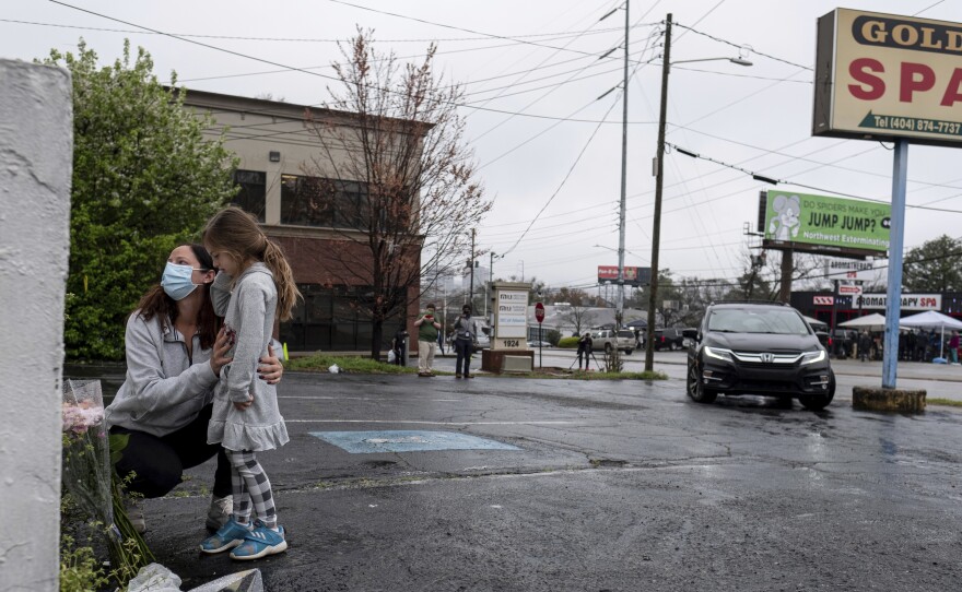 Mallory Rahman and her daughter Zara Rahman, 4, who live nearby, pause after bringing flowers to the Gold Spa massage parlor in Atlanta, Wednesday afternoon, March 17, 2021, the day after eight people were killed at three massage spas in the Atlanta area. Authorities have arrested 21-year-old Robert Aaron Long in the shootings at massage parlors in Atlanta and one in Cherokee County.