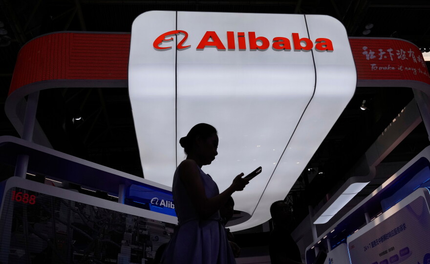 FILE - A visitor walks in front of Alibaba booth during the 3rd China International Supply Chain Expo at the China International Exhibition Center, in Beijing, China, Friday, July 18, 2025.