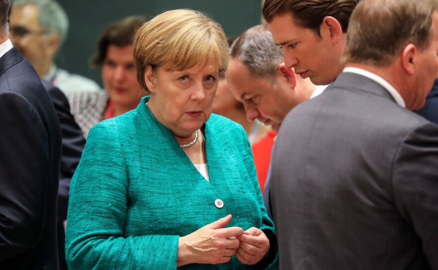 Germany's Chancellor Angela Merkel speaks with other Europen Union leaders during a summit Thursday in Brussels. Earlier in the day she delivered a speech to a restive German parliament, deeply divided over matters of migration.