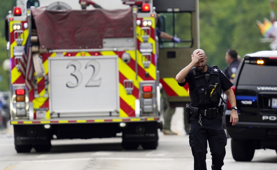 A police officer reacts as he walks in downtown Highland Park, Ill., a suburb of Chicago, Monday, as law enforcement continues a search for the suspected gunman who killed at least six.