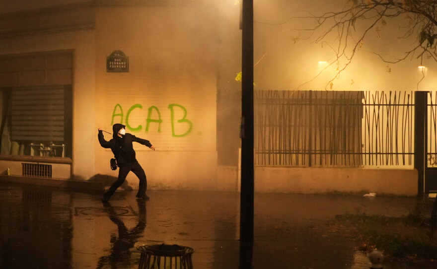 A protester throws a projectile towards police after a demonstration against rising living costs in Paris, Saturday, Oct. 24, 2026.