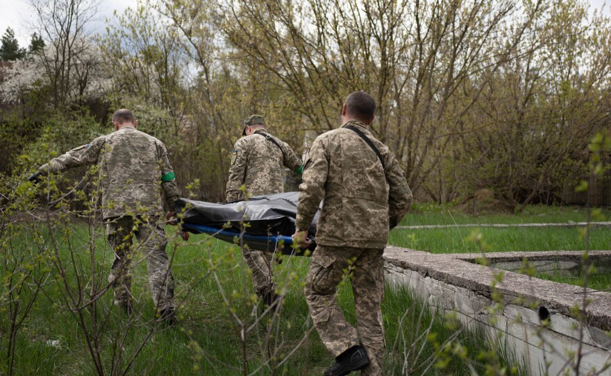 The body of a Russian soldier found in Moshchun is carried away on a stretcher.