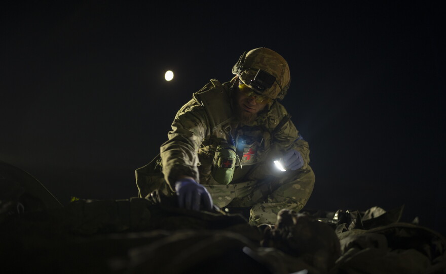 FILE — Oleksiy Yukov examines the body of a Russian soldier he collected on the frontline in the Sloviansk region, Ukraine, Tuesday, Oct. 24, 2023.