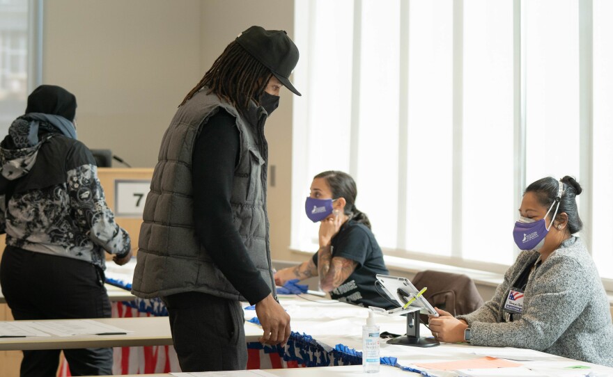Poll workers help voters get ready to cast their ballots at on Nov. 3, 2020 in Atlanta. State lawmakers are now considering legislation that could roll back some laws that made it easy for voters to cast ballots by mail.
