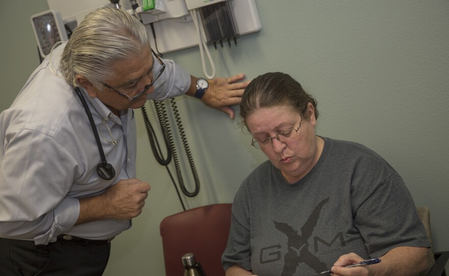 Dr. Ronald Cirillo helps Deborah Hatfield fill out paperwork at a Florida clinic, before running a test to see whether she has hepatitis C.