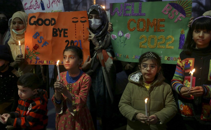 Students holds candles while participating in a demonstration to say goodbye to year 2021 and welcome in 2022, in Lahore, Pakistan, on Friday.