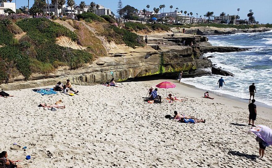 People sunbathing and lounging on the beach at La Jolla Children's Pool beach on May 23, 2020.