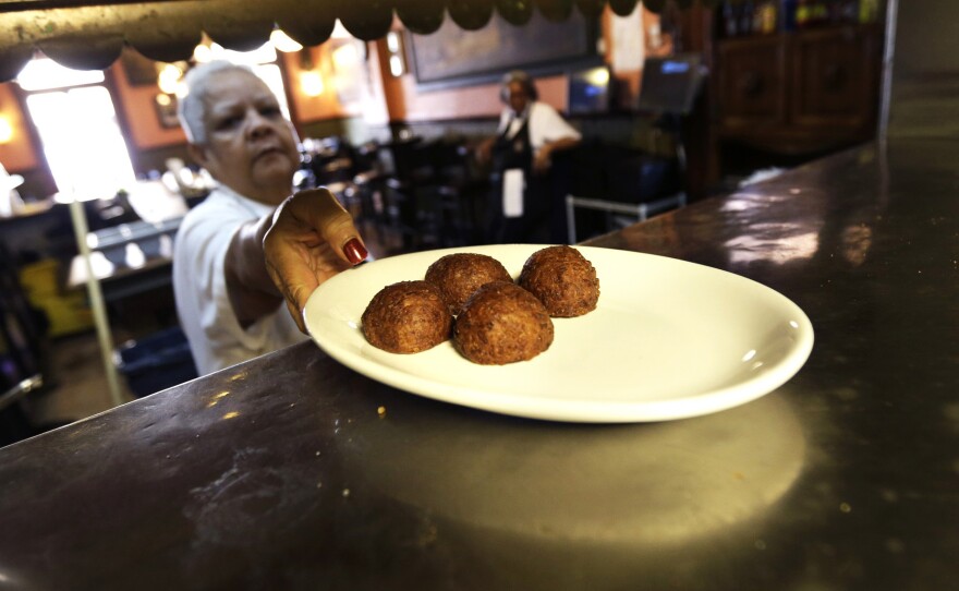 Waitress Gaynell James serves up calas cake from the kitchen at The Old Coffeepot Restaurant in the French Quarter of New Orleans on Jan. 28, 2013.