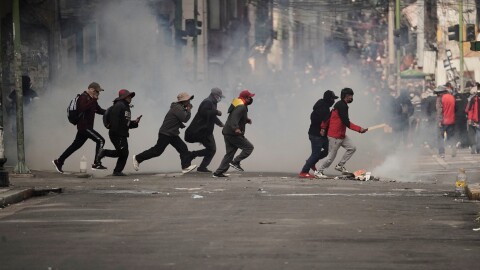 Demonstrators run across a street during an anti-government protest in La Paz, Bolivia, Monday, May 18, 2026.