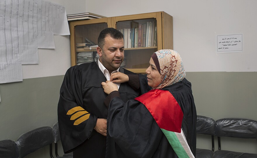 Judge Kholoud helps her husband with his lawyer’s robe.