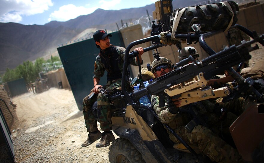 An Afghan soldier rides on the back of a U.S. Green Beret vehicle near the village of Kasan, west of Kabul, in 2013. American combat forces will leave by year's end, but it's not clear how the Afghan forces forces will handle the Taliban threat.