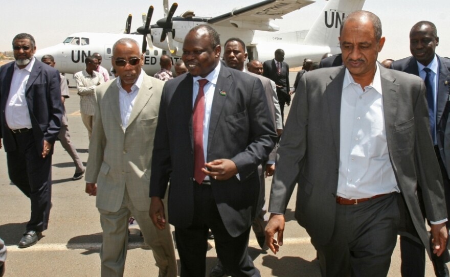  A delegation from South Sudan, headed by Pagan Amum (center), walks with Sudan's Idris Mohamed Abdul-Gadir (right) in Sudan's capital, Khartoum, on March 22. The delegation arrived for a summit between the leaders of the two countries, but the meeting was postponed due to recent tensions. 